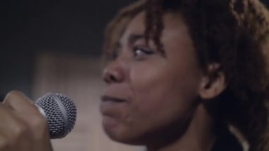 Sahnede şarkı söyleyen mutlu genç Afrikalı şarkıcıya yakın durun.