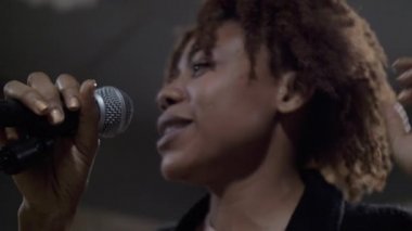 Sahnede şarkı söyleyen genç Afrikalı şarkıcıya yakın çekim