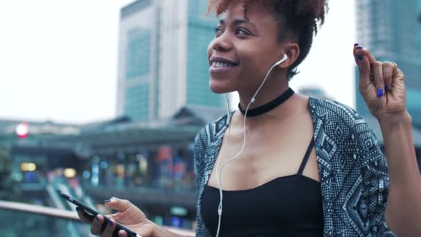 Gelukkig Afrikaans jong vrouw genieten van muziek in de straat — Stockvideo