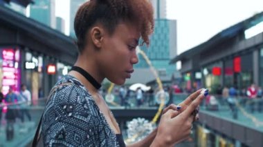 Çin caddesinde cep telefonu kullanarak gezen Afrikalı genç bir kadın.