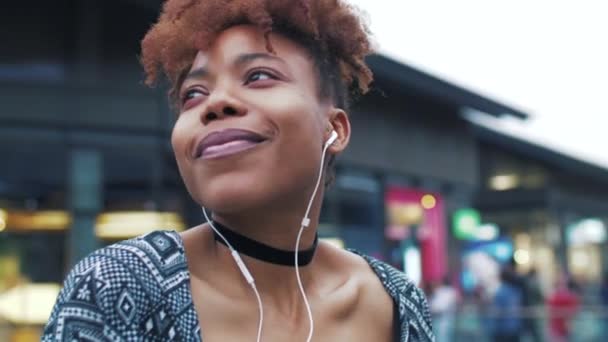 Happy Black jonge vrouw genieten van muziek in de straat — Stockvideo