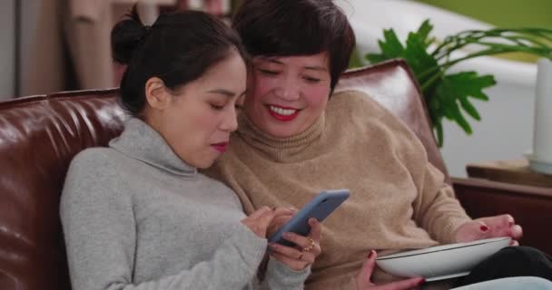 Bastante mujer asiática jugando teléfono móvil con mamá de mediana edad — Vídeo de stock