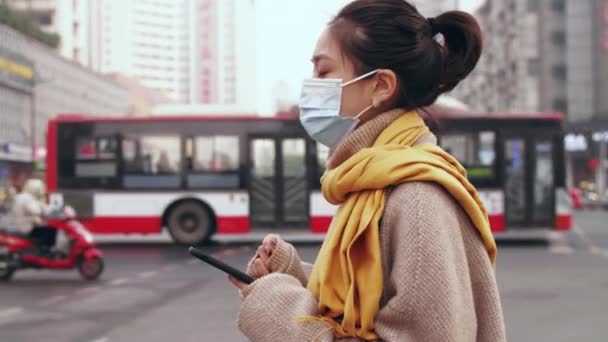 在城市里，亚洲女孩戴着面具，用手机 — 图库视频影像