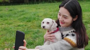 Çinli bir kadın akıllı telefondan köpekle selfie çekiyor..
