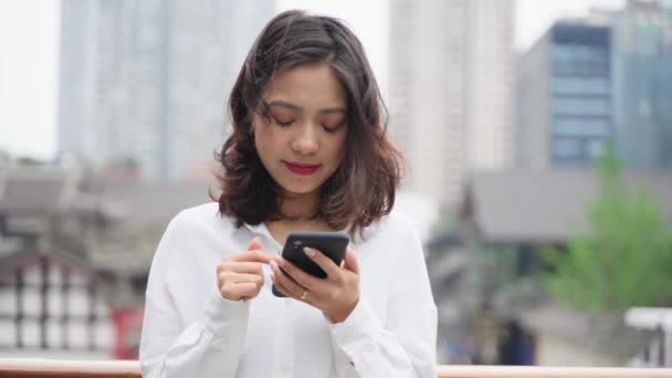 pěkný mladý asijské žena pomocí mobilního telefonu v městském městě 4k zpomalení kamera pohybující se blízko okouzlující dáma při pohledu na chytrý telefon