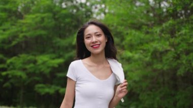 4k ağır çekim güzel Asyalı kız bahar parkında yürüyor güzel günün tadını çıkar güzel çekici genç bayan dışarıda dinleniyor