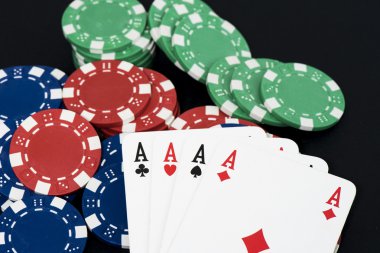 İskambil ve fişleri siyah masada, dört bir tür Aslar