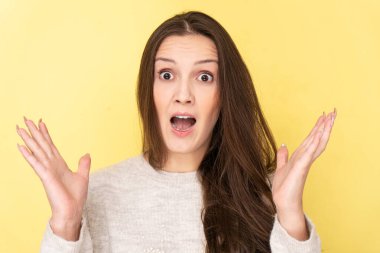 Tatar esmer kız ellerini açık ağızla ıslatıyor ve sarı stüdyoda izole edilmiş şaşırmış bir yüz ifadesi var. İyi haber, satış konsepti.
