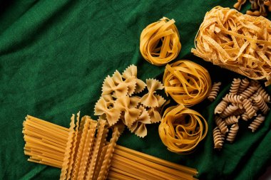 Yeşil kumaş arka planda değişik makarna çeşitleri, çeşitli makarna konsepti.