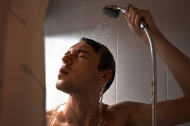 Genç yakışıklı adamın portresi kendini duş jeliyle yıkar, başını şampuanla yıkar.