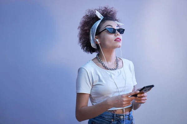 Trendiges Mädchen Mit Afro Locken Nutzt Smartphone Und Kopfhörer Auf — Stockfoto