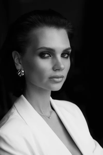 Black and white fashion portrait of a beautiful luxurious woman in a white jacket, professional makeup and glamorous accessories