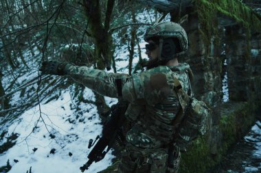 Ormanda makineli tüfekle profesyonel ekipman içinde uçan yumuşak oyuncunun portresi. Savaşta silahlı bir asker