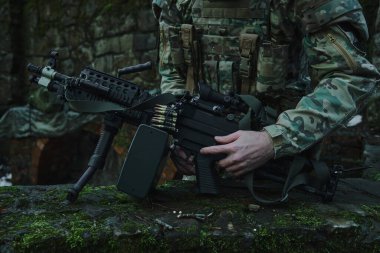 Profesyonel ekipmanlı havalı oyuncunun portresi ormanda bir silaha kurşun dolduruyor. Savaşta silahlı bir asker