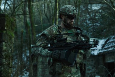 Ormanda makineli tüfekle profesyonel ekipman içinde uçan yumuşak oyuncunun portresi. Savaşta silahlı bir asker