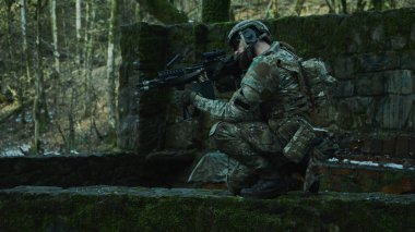 Ormanda makineli tüfekle profesyonel ekipman içinde uçan yumuşak oyuncunun portresi. Savaşta silahlı bir asker