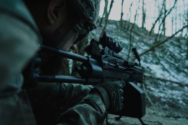 Profesyonel ekipmanlı, kasklı, havalı oyuncunun portresi ormanda silahla kurbana nişan alıyor. Savaşta silahlı bir asker