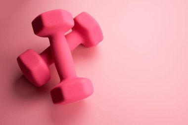 İki pembe kadın dambıl, arka planda izole edilmiş, fotokopi alanı ile yakın plan. Fitness konsepti, kilo kaybı ve spor aktivitesi, üst görünüm, düz yatış