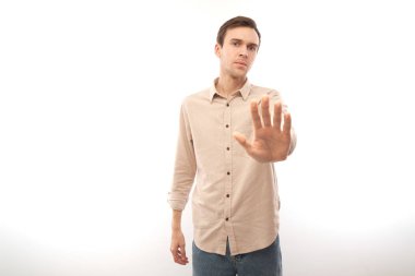 Esmer adamın portresi, dur işareti yapıyor. Hayır, lütfen. Beyaz stüdyo arka planında izole edilmeyi reddediyorsunuz.