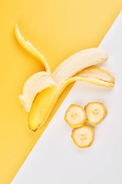 Yarısı soyulmuş muz ve sarı beyaz arkaplandaki dilimler kopya alanı ile