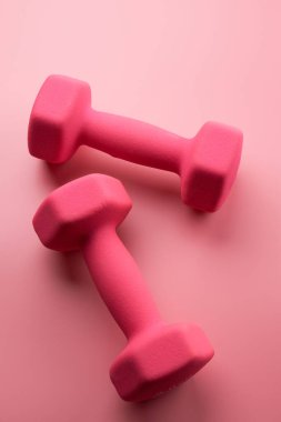 İki pembe kadın dambıl, arka planda izole edilmiş, fotokopi alanı ile yakın plan. Fitness konsepti, kilo kaybı ve spor aktivitesi
