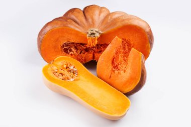 Beyaz yemek arka planında iki farklı çiğ portakal kabağı var.