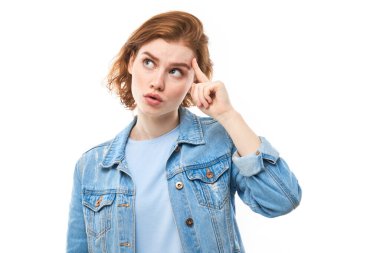 Portrait of young attractive beautiful thoughtful happy redhead female student thinking looking at copyspace, isolated on white background. Woman in blue jeans