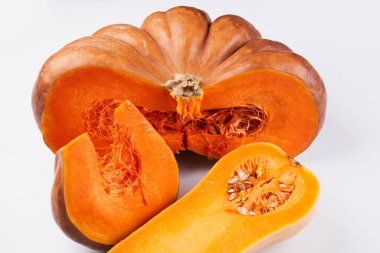 Beyaz yemek arka planında iki farklı çiğ portakal kabağı var.