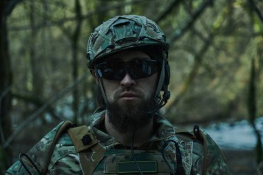 Ormanda makineli tüfekle profesyonel ekipman içinde uçan yumuşak oyuncunun portresi. Savaşta silahlı bir asker