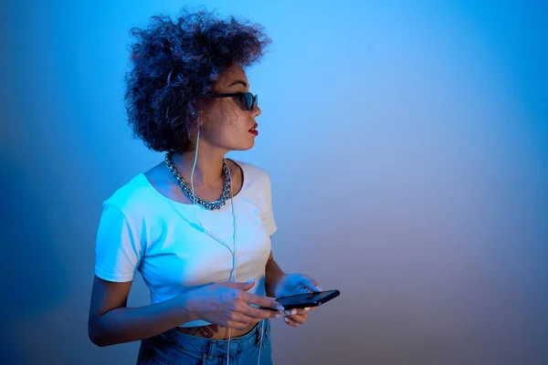 Trendiges Mädchen Mit Afro Locken Nutzt Smartphone Und Kopfhörer Auf — Stockfoto