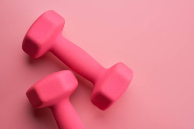 İki pembe kadın dambıl, arka planda izole edilmiş, fotokopi alanı ile yakın plan. Fitness konsepti, kilo kaybı ve spor aktivitesi, üst görünüm, düz yatış