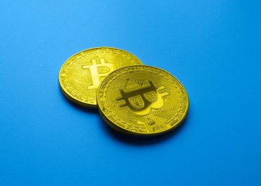 Mavi zemin üzerinde iki altın bitcoin izole edilmiş fotokopi alanı ile yakın plan, büyüme ve kripto para düşüşü kavramı