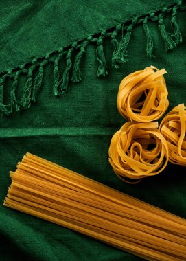 Yeşil kumaş arka planda değişik makarna çeşitleri, çeşitli makarna konsepti.