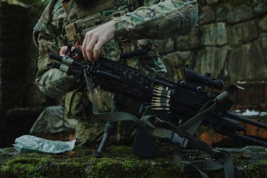 Profesyonel ekipmanlı havalı oyuncunun portresi ormanda bir silaha kurşun dolduruyor. Savaşta silahlı bir asker