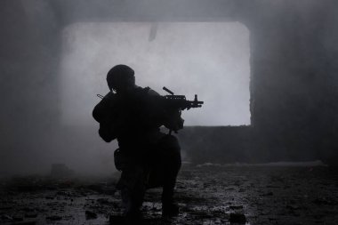Arka planda silahı olan profesyonel havalı oyuncunun portresi yıkılmış bir bina. Sis ve duman içinde silahlı bir asker, siyah beyaz bir fotoğraf