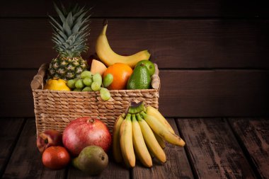 Tahta arka planda sepette taze renkli egzotik meyvelerin karışımı.