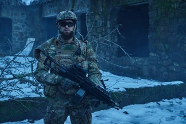 Terk edilmiş binada makineli tüfekle profesyonel ekipman içinde havalı oyuncunun portresi. Savaşta silahlı bir asker