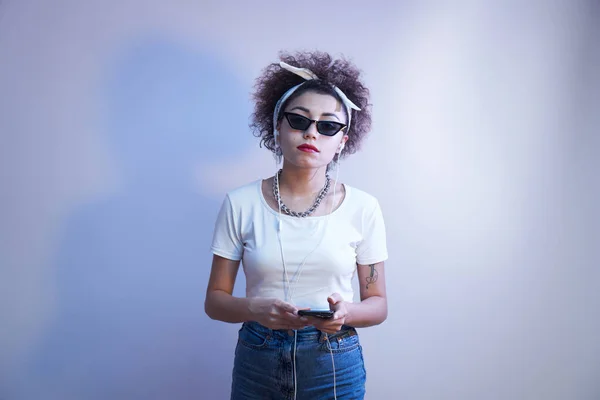 Trendy Girl Afro Curls Uses Smartphone Earphones Blue Studio Background — Stock Photo, Image