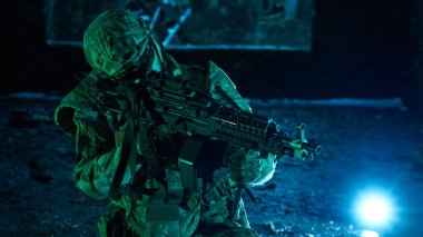 Terk edilmiş binada makineli tüfekle profesyonel ekipman içinde havalı oyuncunun portresi. Savaşta silahlı bir asker