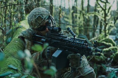 Profesyonel ekipmanlı, kasklı, havalı oyuncunun portresi ormanda silahla kurbana nişan alıyor. Savaşta silahlı bir asker