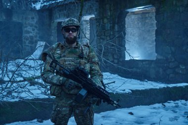 Terk edilmiş binada makineli tüfekle profesyonel ekipman içinde havalı oyuncunun portresi. Savaşta silahlı bir asker