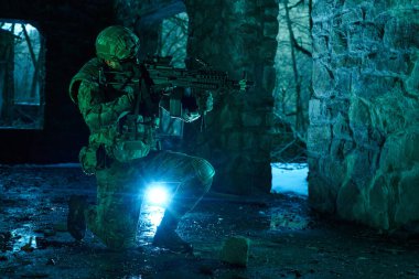 Terk edilmiş binada makineli tüfekle profesyonel ekipman içinde havalı oyuncunun portresi. Savaşta silahlı bir asker