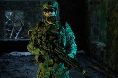 Terk edilmiş binada makineli tüfekle profesyonel ekipman içinde havalı oyuncunun portresi. Savaşta silahlı bir asker