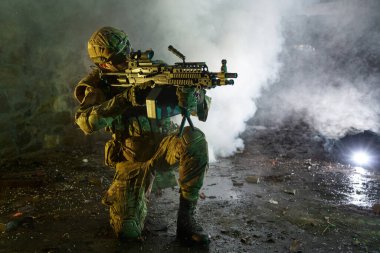 Terk edilmiş binada makineli tüfekle profesyonel ekipman içinde havalı oyuncunun portresi. Savaşta sisli ve dumanlı silahlı asker