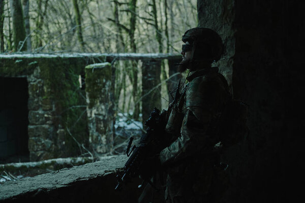 Portrait of airsoft player in professional equipment with machine gun in the forest. Soldier with weapons at war