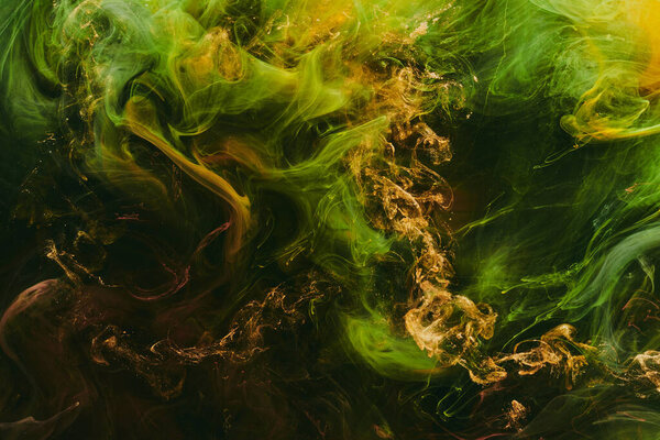 Абстрактный красочный дым, темный фон. Движущийся поток желтых и зеленых красок, жидкое искусство