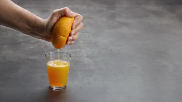 Χέρι συμπίεση ενός πορτοκαλιού σε ένα ποτήρι — Αρχείο Βίντεο