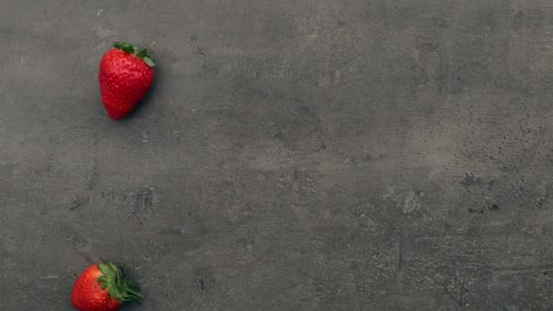 Fallande jordgubbar på grå bord — Stockvideo