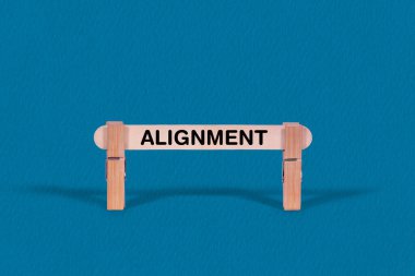 Tek tahta sopa, iş ve hizalama kavramını temsil eden serin mavi bir arka planda mandallarla sınırlı..