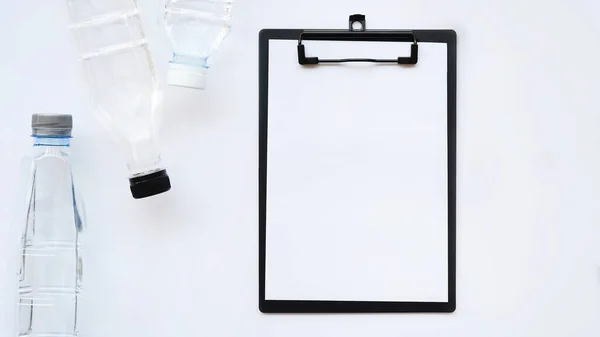 close up of empty paper and bottle of water isolated on white background